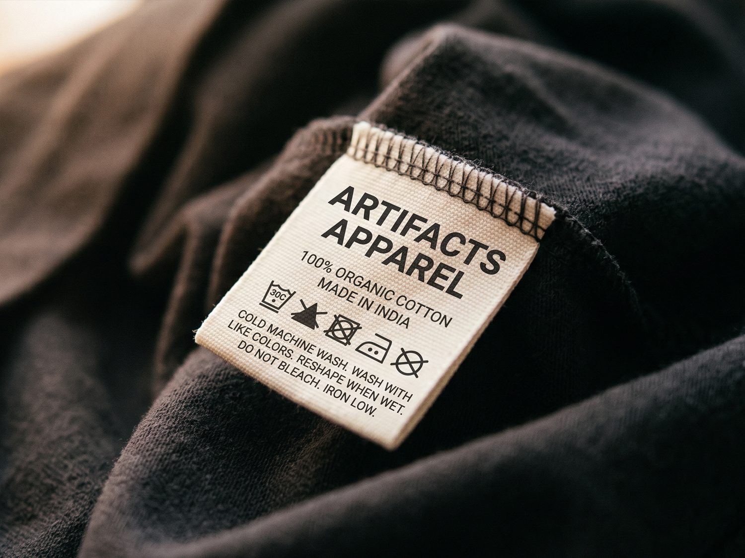 A blank white garment tag hanging against deep red fabric.